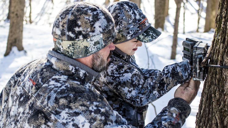 A man and child look at a hunting trail camera.