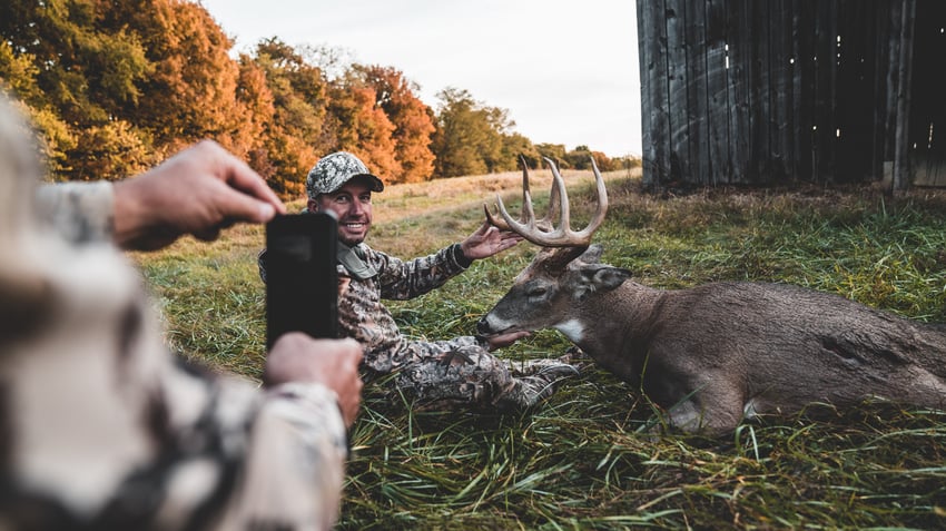 Taking a photo of a hunter and trophy buck after harvest.