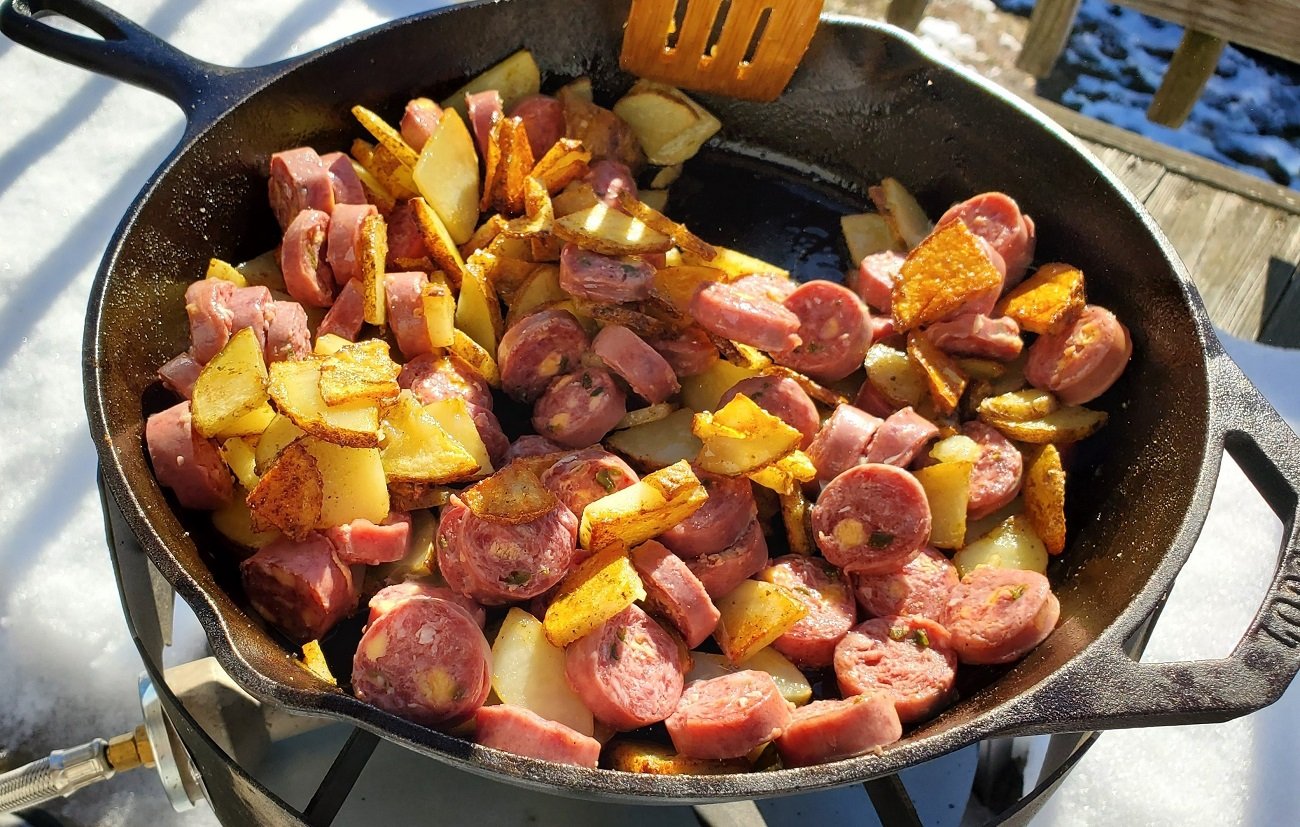 Cooking venison kielbasa over an outdoor propane stove.